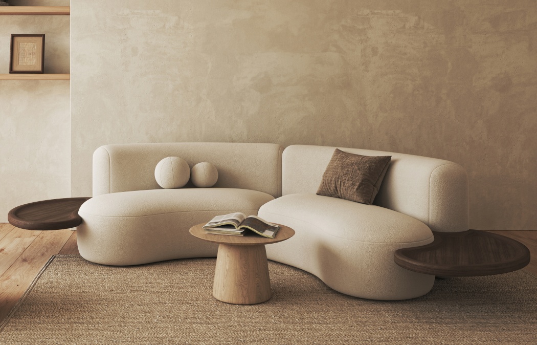 Curved beige sofa with integrated wooden side tables, a round coffee table, and a brown cushion, set on a woven rug in a neutral-toned living room.