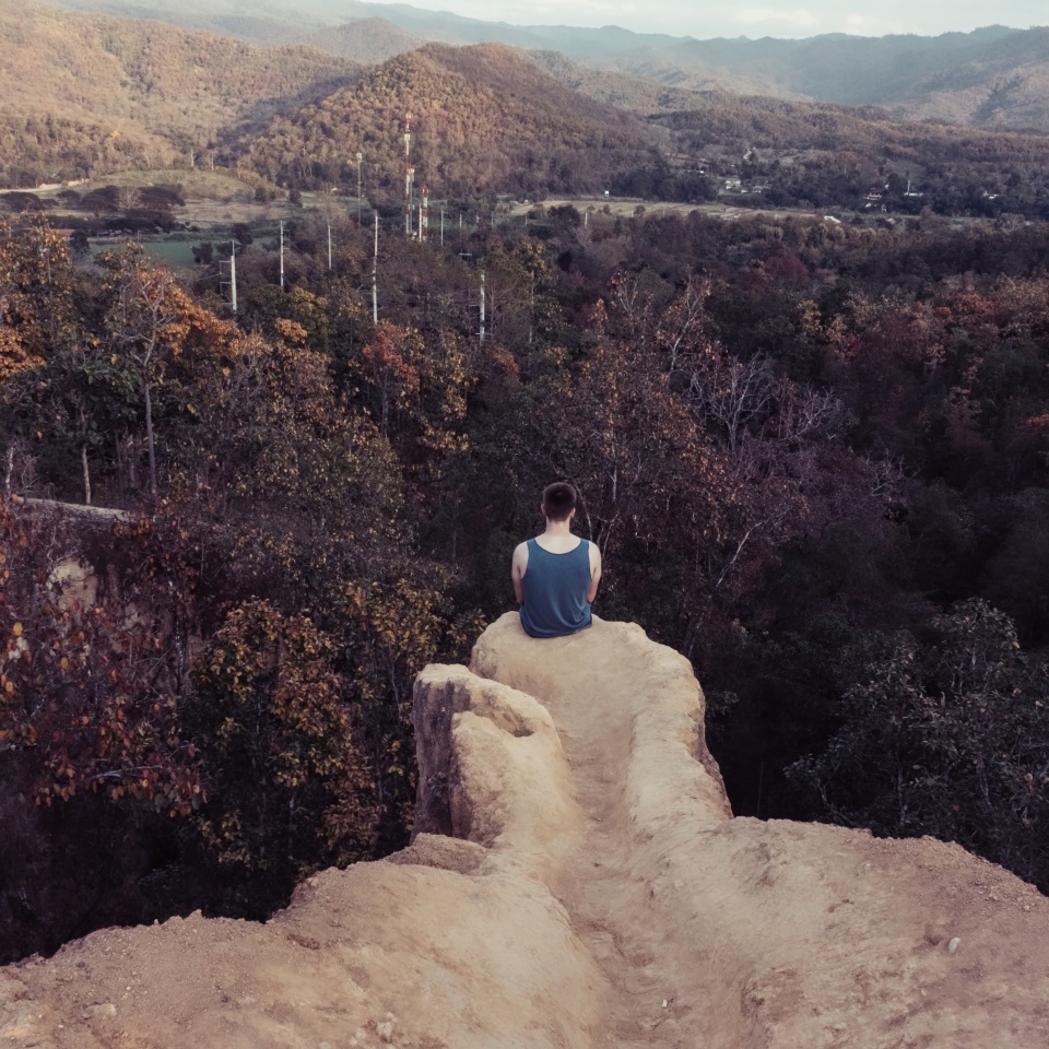 Unhappy lonely depressed young man sitting on the edge of mountain hill contemplating suicide, Concept of unemployed, sadness, depression,low self-esteem broken heart and Major depressive disorder