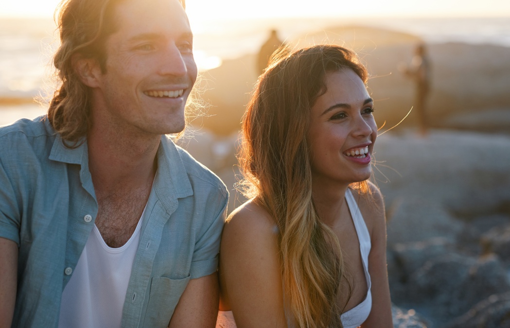 happy couple smiling on beach at sunset enjoying summer