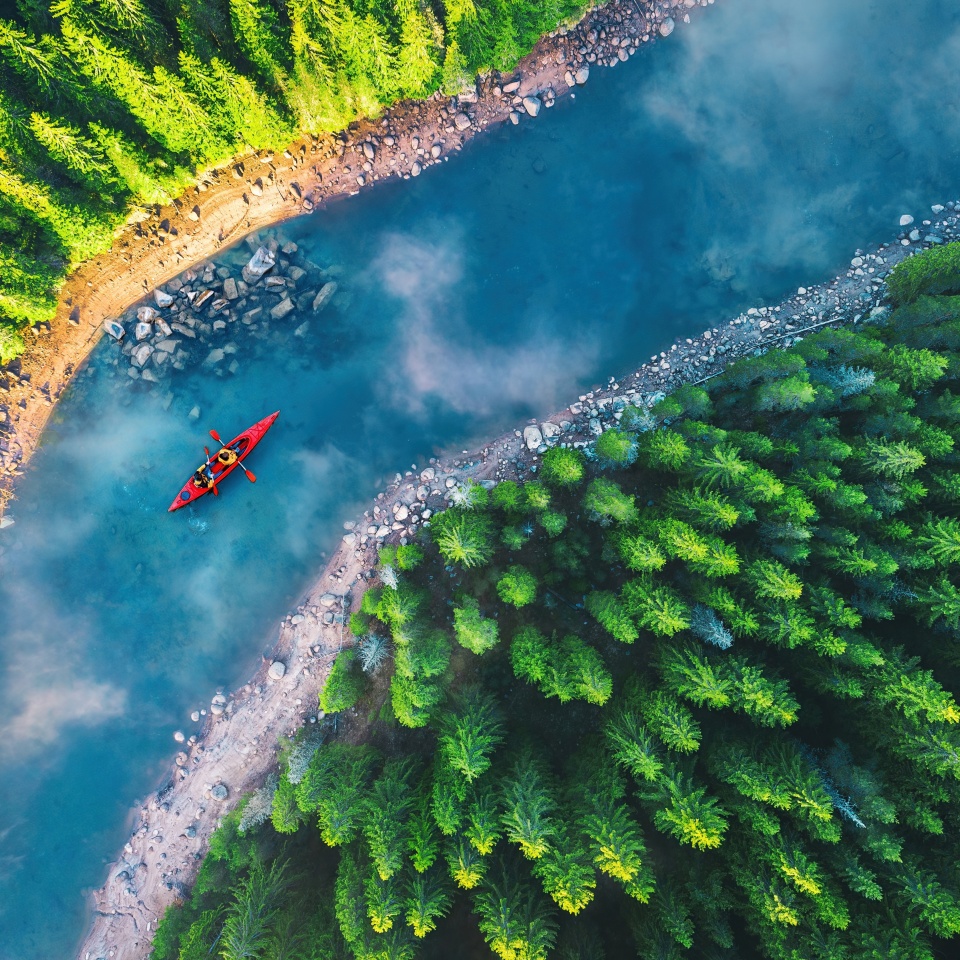 Aerial view of rafting boat or canoe in mountain river and forest. Recreation camping and sport lifestyle