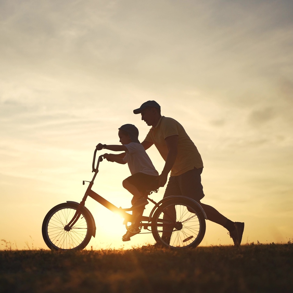 Happy family. dad teaches his son to ride bike. happy family kid dream concept. silhouette of a child riding a bicycle. silhouette of a father teaching his son lifestyle to ride a bicycle.