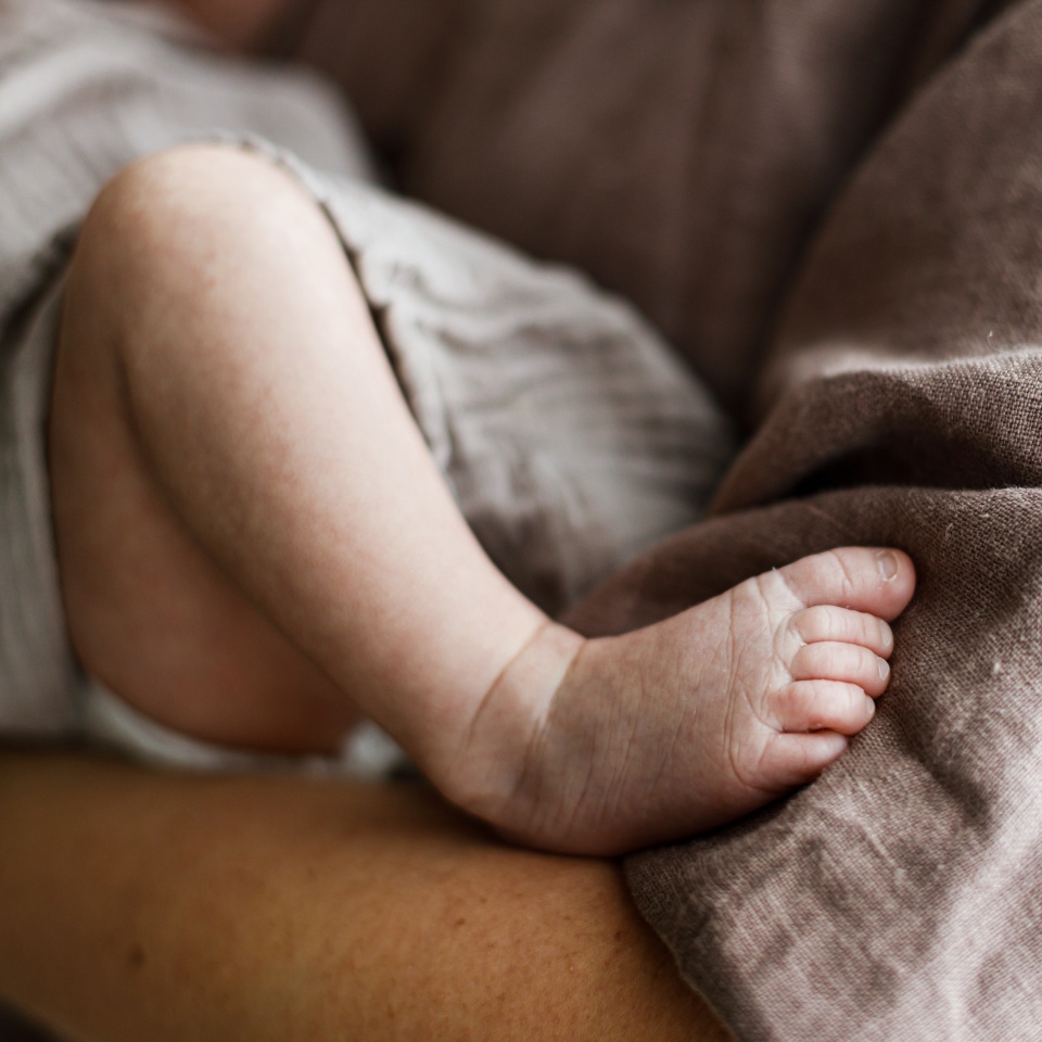Happy Mothers day! Newborn little feet close up in mothers hands. Mother hugging cute baby. Motherhood and parenthood. Adoption and fertility concept